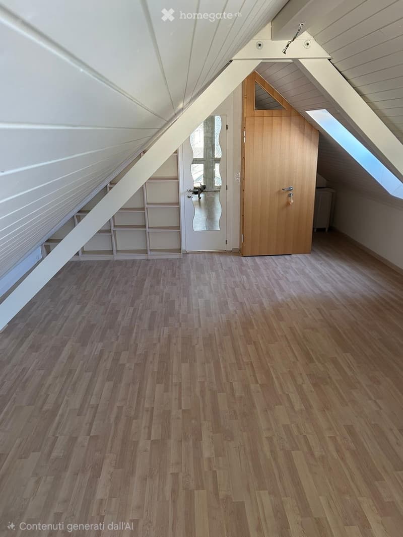 Empty attic room with wooden flooring, slanted white ceiling, wooden door, and built-in shelving unit.