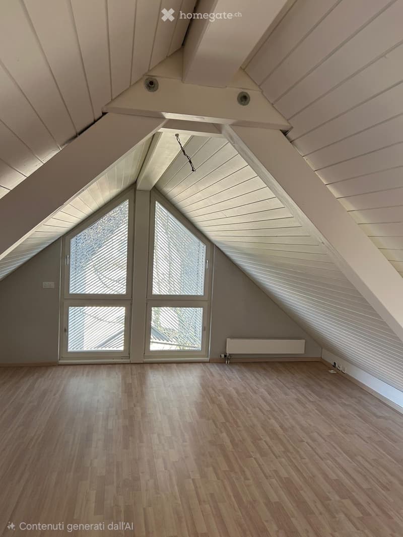 Empty attic space with wooden flooring, slanted white ceilings, and large windows with blinds. No furniture or equipment present.