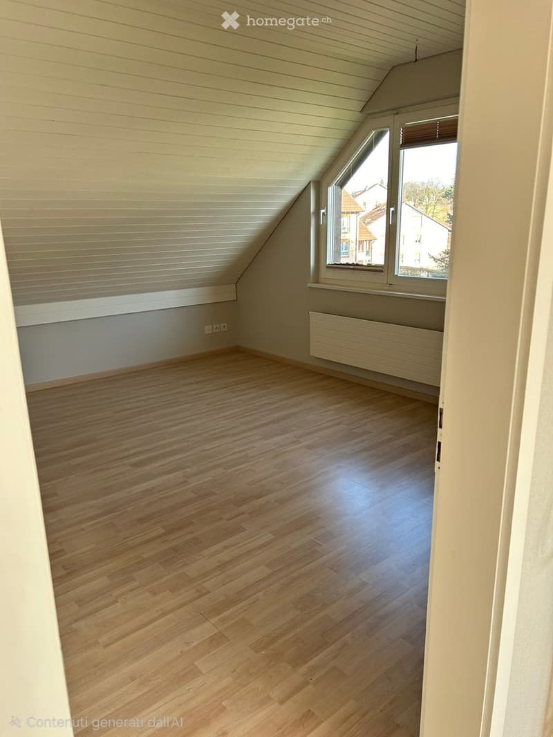 Empty attic room with wooden flooring, slanted ceiling, large window, radiator, and electrical outlets.
