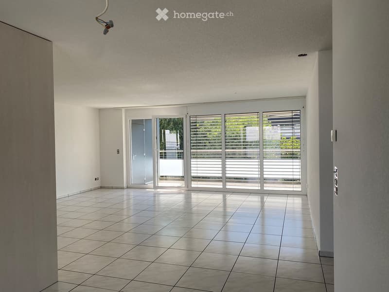 Empty room with tiled floor, white walls, large sliding glass doors leading to an outdoor area, and visible electrical outlets.