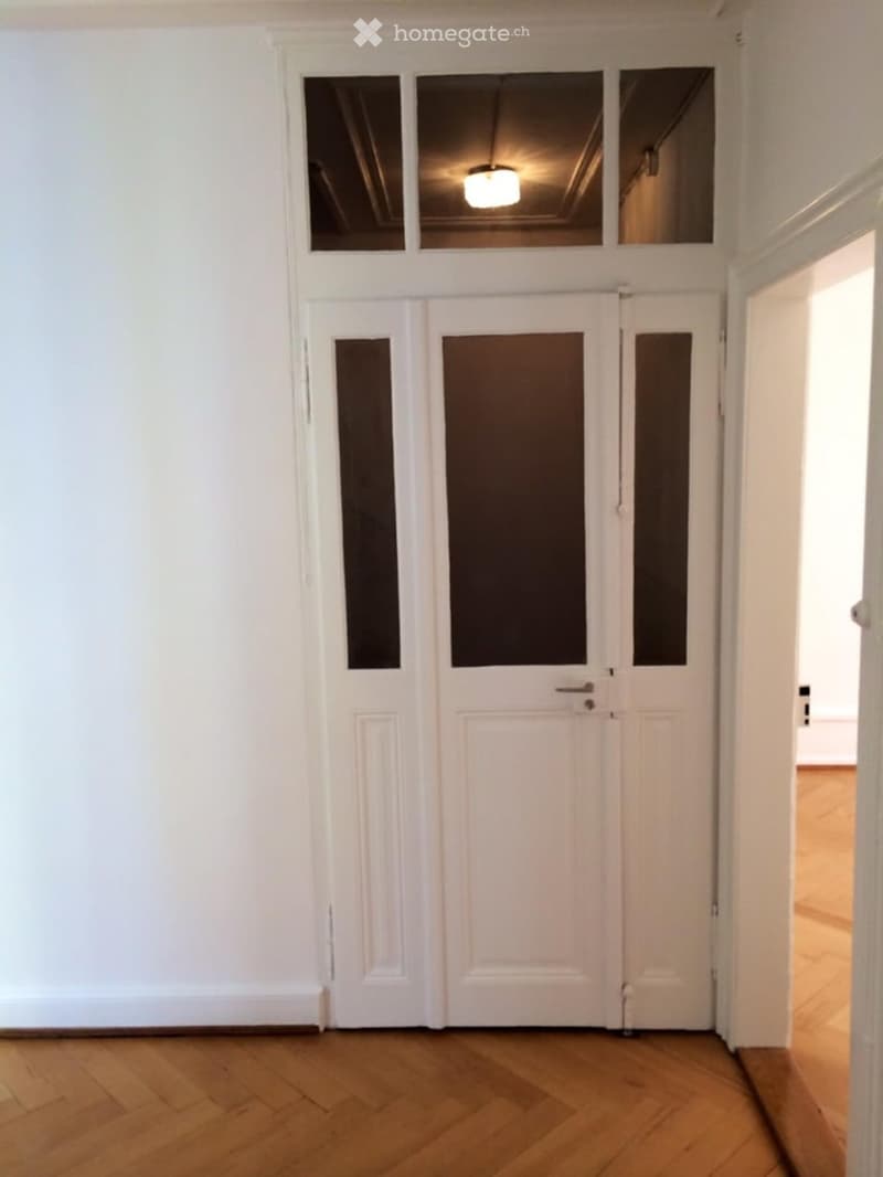 white doors, wooden floor, bright light from hallway