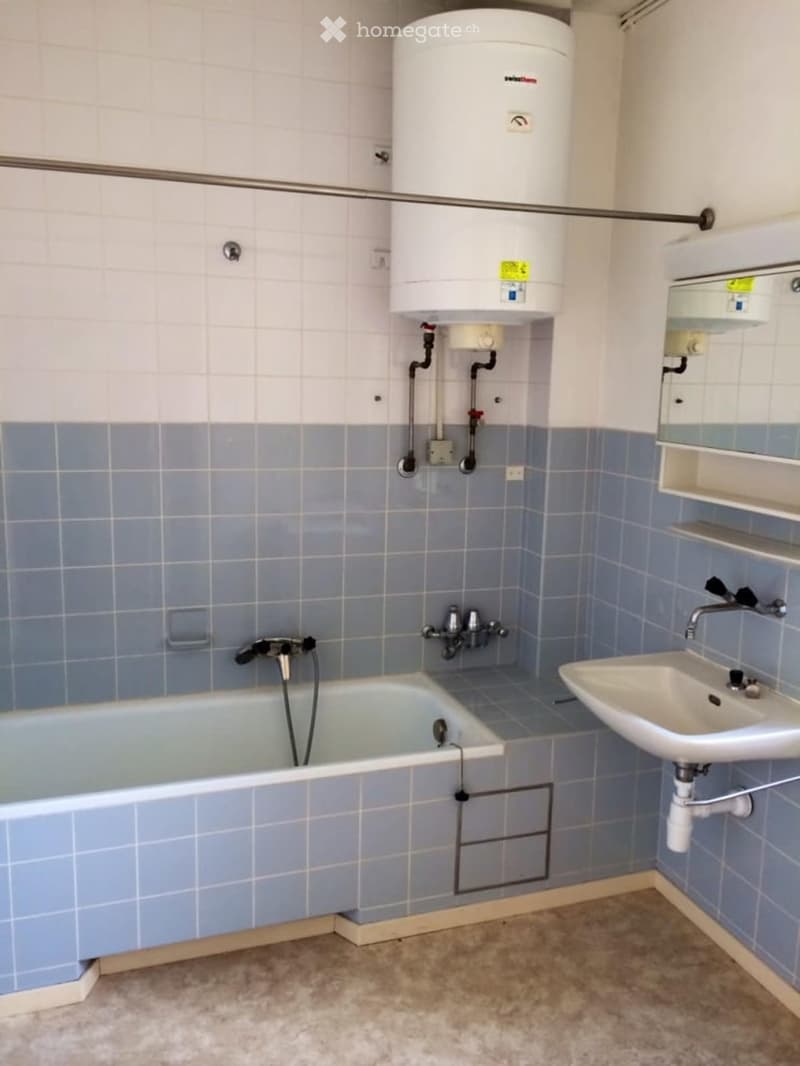 Bathroom with bathtub, sink, mirror and water heater