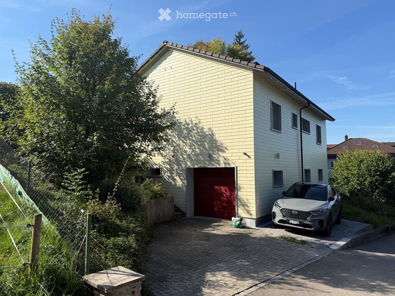Two-story house with beige brick exterior, red garage door, and a parked car in front.