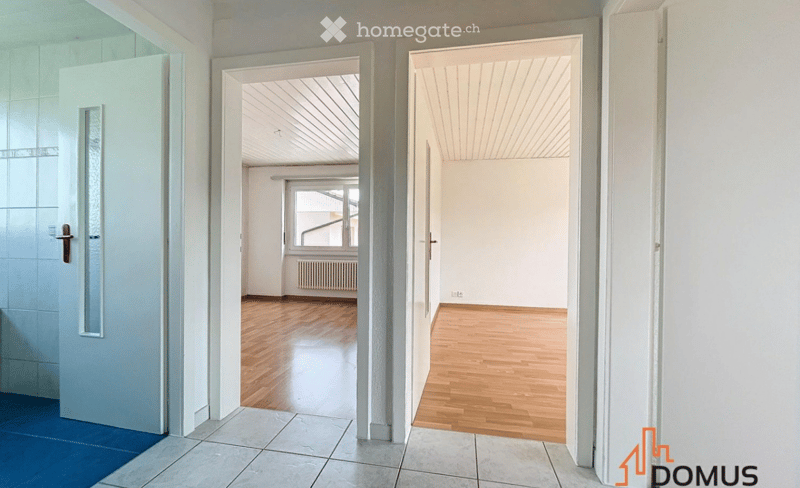 Empty hallway with wooden flooring, white walls, and multiple open doors leading to adjacent rooms.