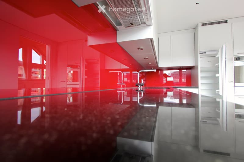 Modern kitchen with red walls, white cabinets, stainless steel sink, and a sleek countertop.