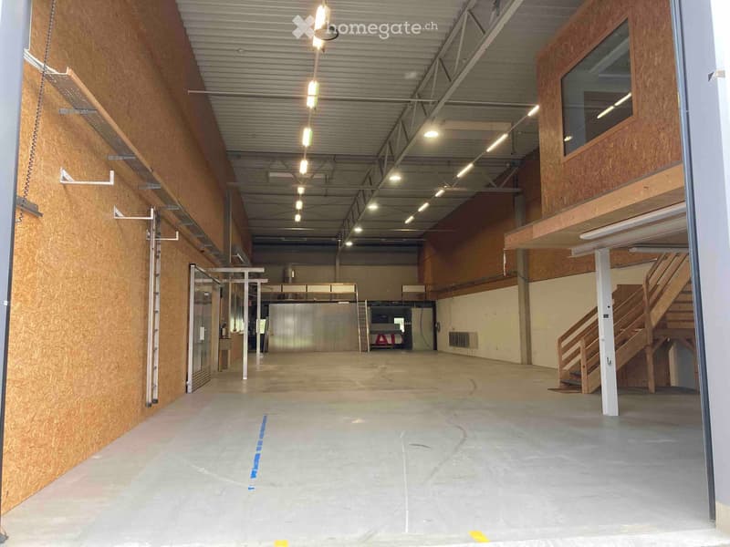 Empty industrial-style room with exposed metal ceiling, wooden walls, and a staircase leading to an upper level. No furniture or equipment is present.