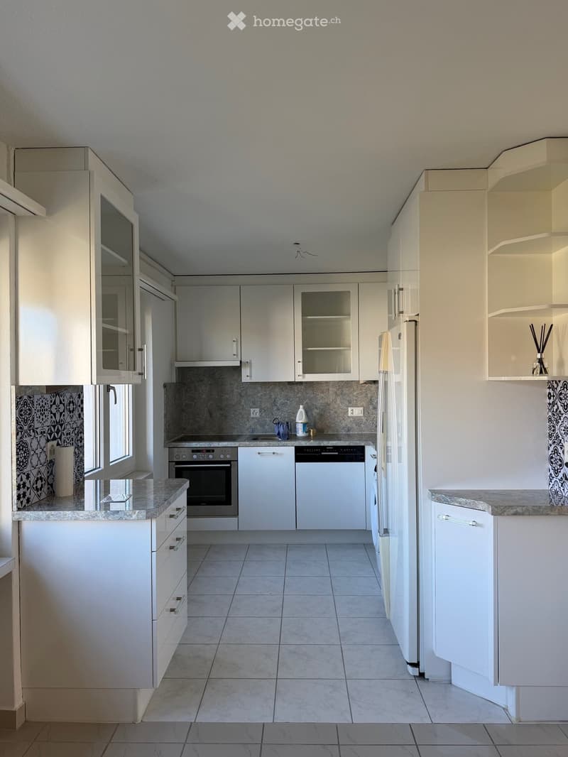 Modern kitchen with white cabinets, granite countertops, and stainless steel appliances including a refrigerator, oven, and dishwasher.