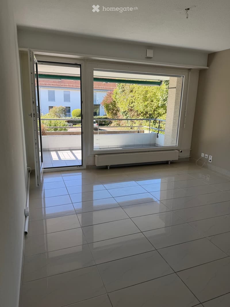 Empty room with large sliding glass doors leading to a balcony, tiled floor, and visible electrical outlets.