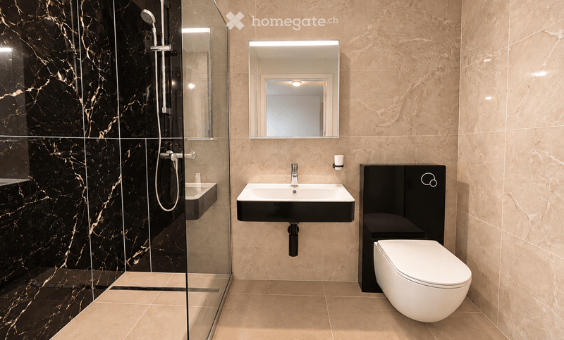 Modern bathroom with beige marble tiles, black accents, a glass-enclosed shower, a white toilet, and a black sink with a mirror above it.