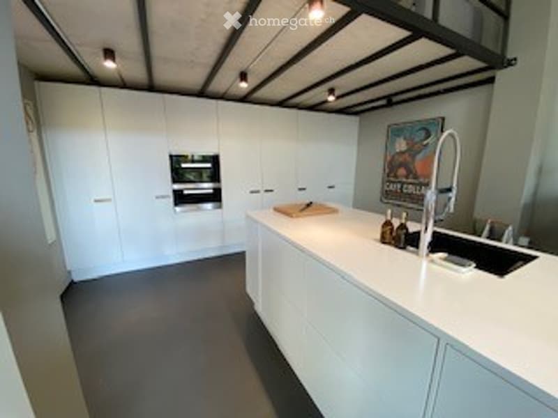 Modern, minimalist kitchen with white cabinets, a central island, and stainless steel appliances.