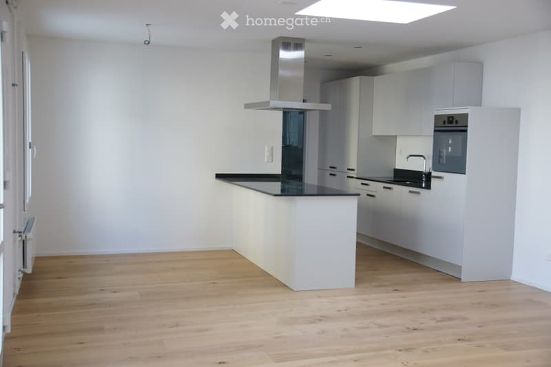 Modern kitchen with white cabinets, a black countertop, a kitchen island, and a stainless steel range hood.