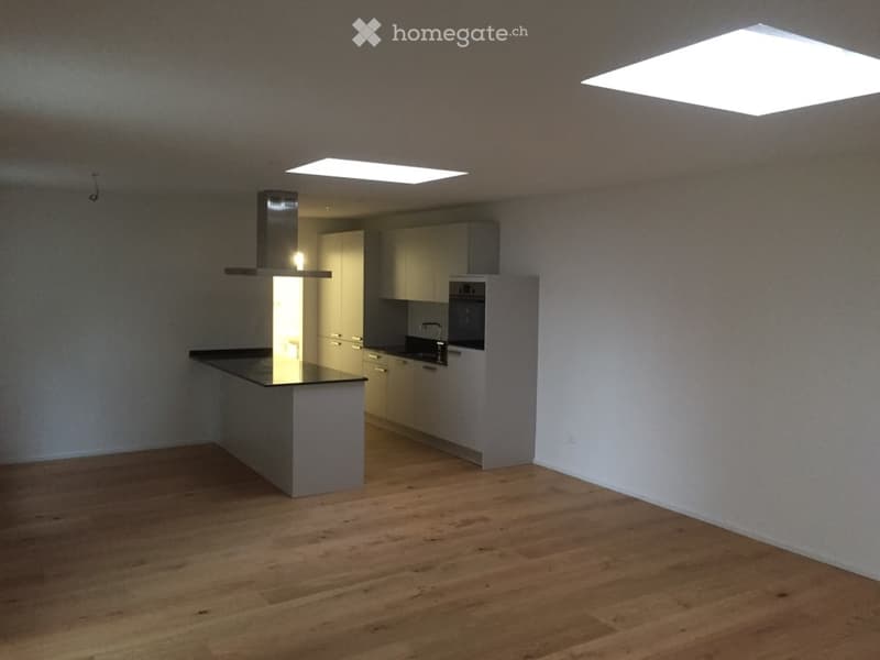Modern kitchen with light-colored cabinets, a central island, and a range hood. The floor is made of light wood, and the space is well-lit with ceiling lights.