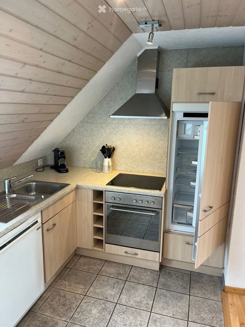 Modern kitchen with wooden cabinets, stainless steel appliances, and a tiled floor. Features include a sink, oven, refrigerator, coffee maker, and range hood.