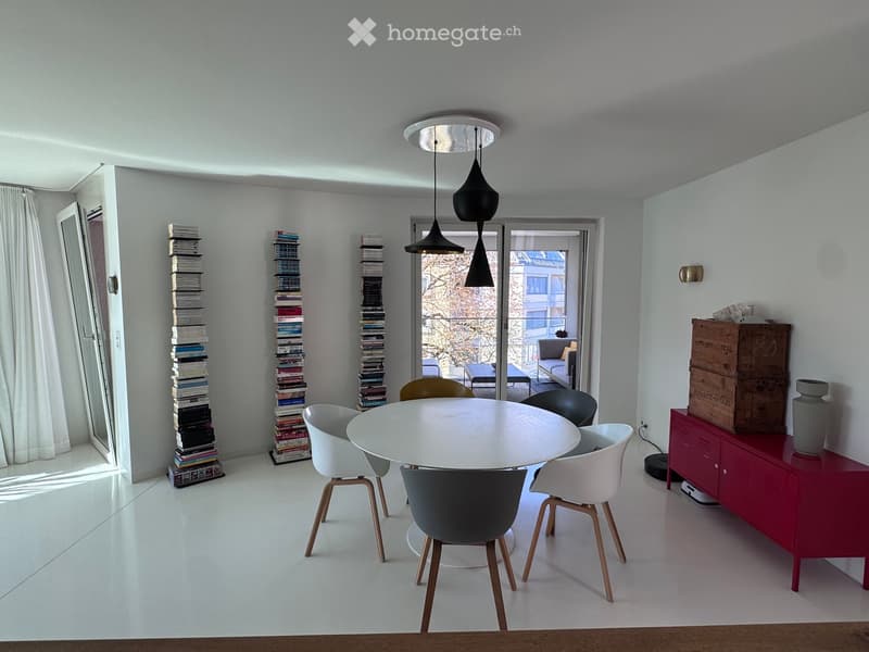 Modern dining area with white dining table, chairs, red cabinet, and decorative items.