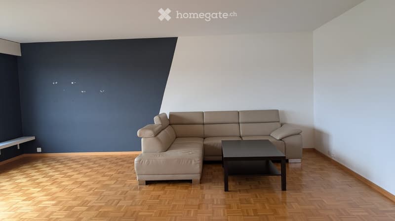 Modern living room with a light-colored sectional sofa, a black coffee table, and wooden flooring.