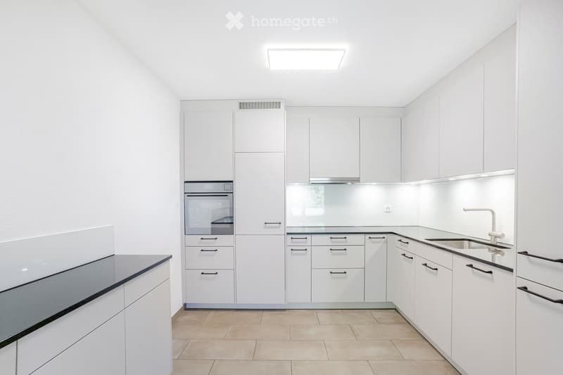 Modern, minimalist kitchen with white cabinets, stainless steel appliances, and a sleek design.