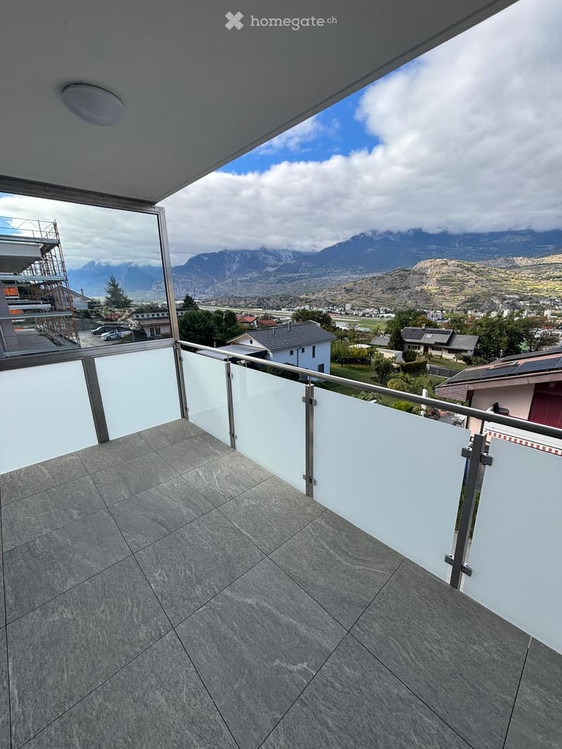 Balcony with modern glass railing, tiled floor, and scenic mountain view.
