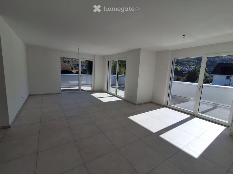 Empty room with tiled floor, large sliding glass doors leading to a balcony, and natural light streaming in.