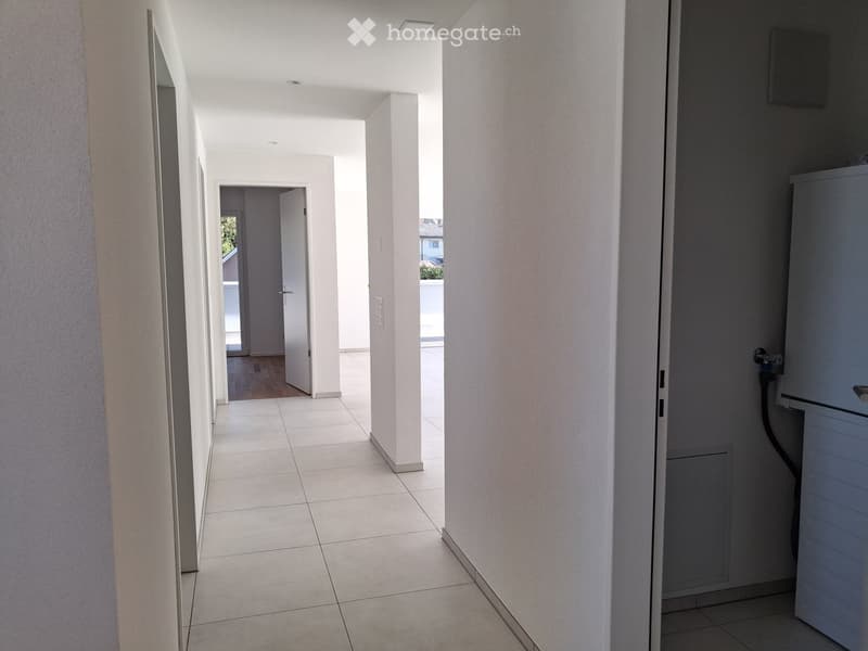Empty hallway with tiled floor, white walls, and several doors leading to other rooms.