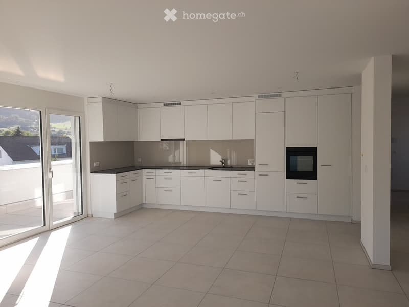 Modern, minimalist kitchen with white cabinets, a central island, and a built-in oven. The space features large windows and a tiled floor.
