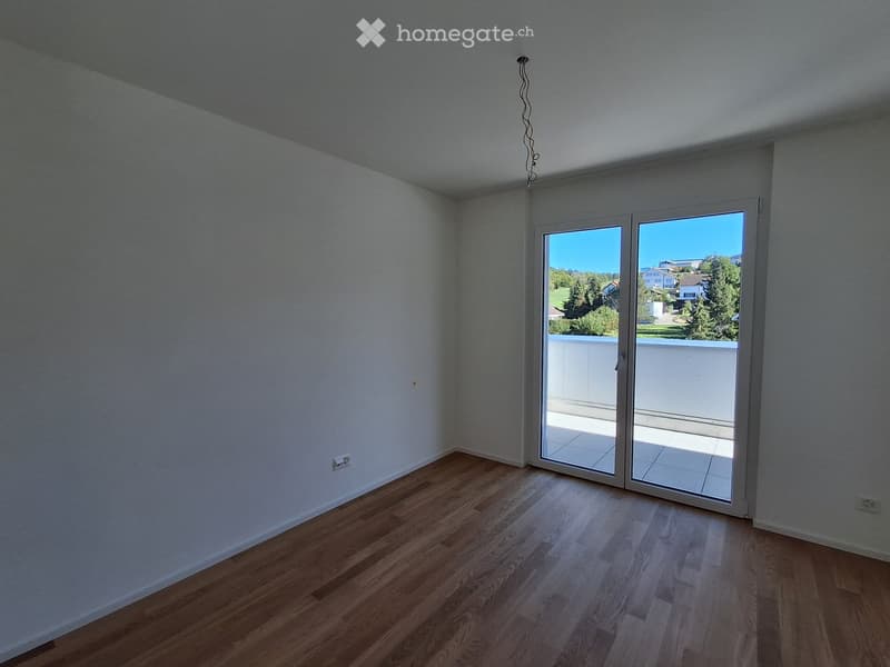 Empty room with wooden flooring, white walls, and large sliding glass doors leading to a balcony.