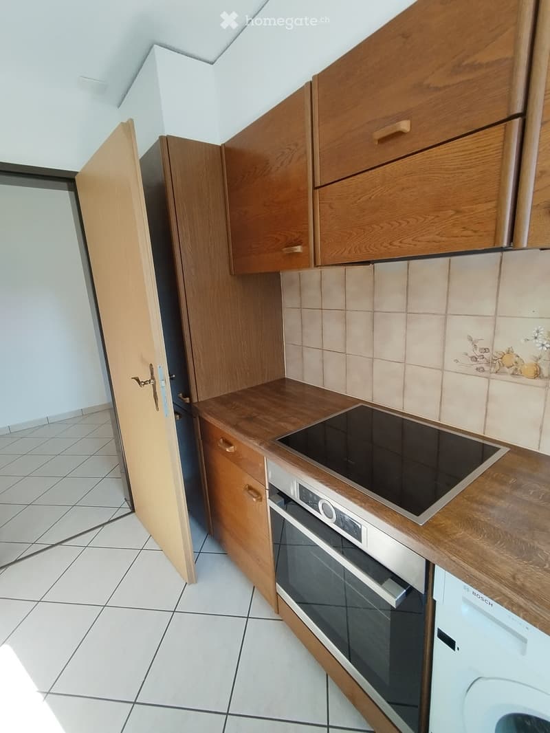 Modern kitchen with wooden cabinets, an induction stove, an oven, and a Bosch dishwasher. The countertops are made of wood, and the backsplash features floral tiles.