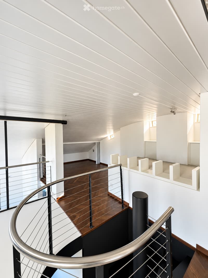 Modern interior staircase with wooden steps, metal railings, white walls, and a sleek design.