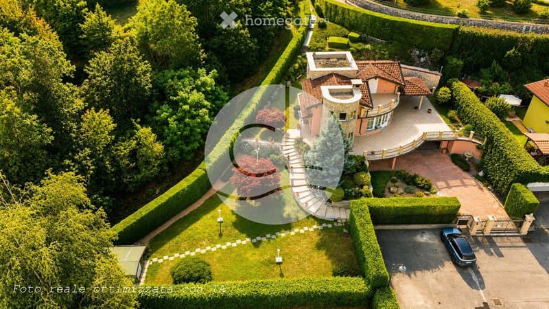 Aerial view of a large, modern house with a well-maintained garden, driveway, and garage.