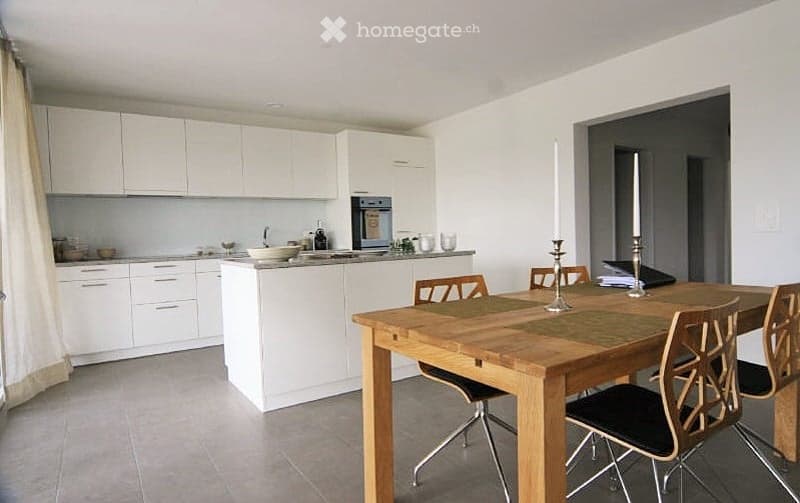 Modern kitchen with white cabinets, a central island, and a wooden dining table with chairs.