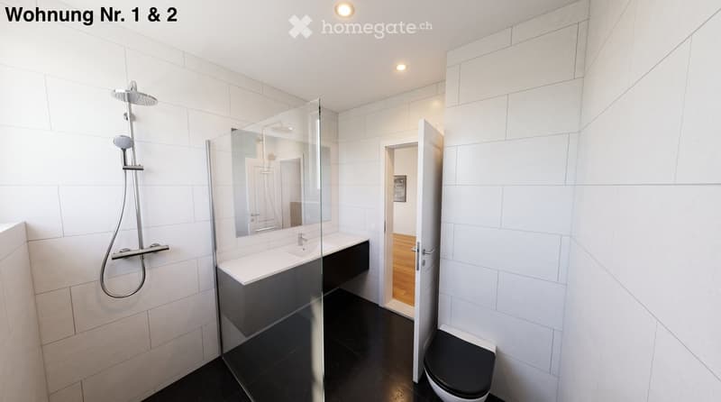 Modern bathroom with white tiles, glass shower enclosure, black countertop sink, and a toilet.