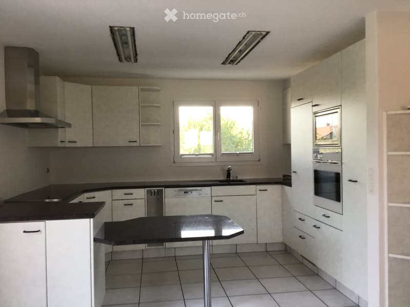Modern kitchen with white cabinets, black countertops, and built-in appliances including a dishwasher and oven. Features a central island with a black countertop and a sink with a faucet.