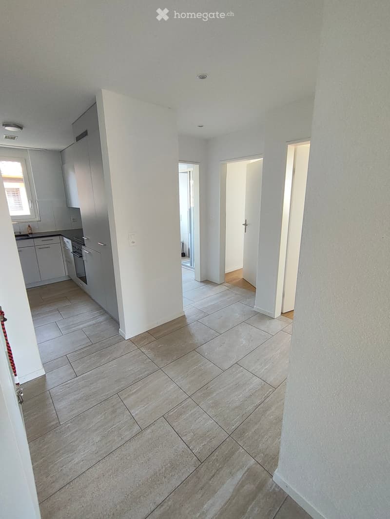 Empty hallway with tiled floor, white walls, and several open doors leading to other rooms.