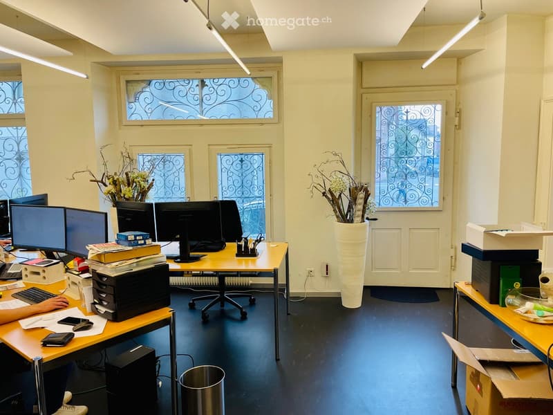 Office space with desks, computers, chairs, and decorative vases.