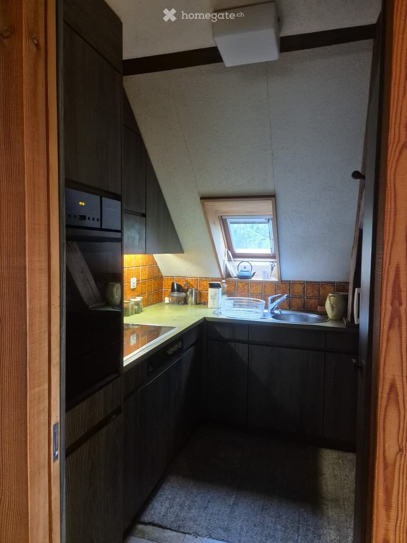 Modern kitchen with dark wooden cabinets, a sink, microwave, and various kitchen items on the counter.