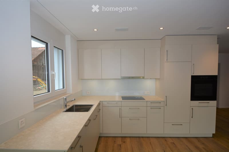 Modern kitchen with white cabinets, granite countertops, a sink, and an oven. The space features large windows and recessed lighting.