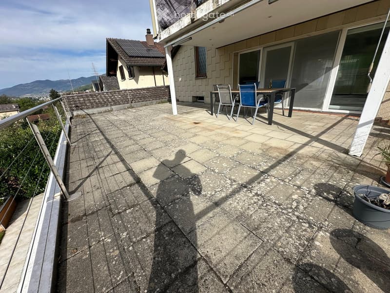 Balcony with concrete floor, metal railing, and outdoor furniture including a table and chairs.