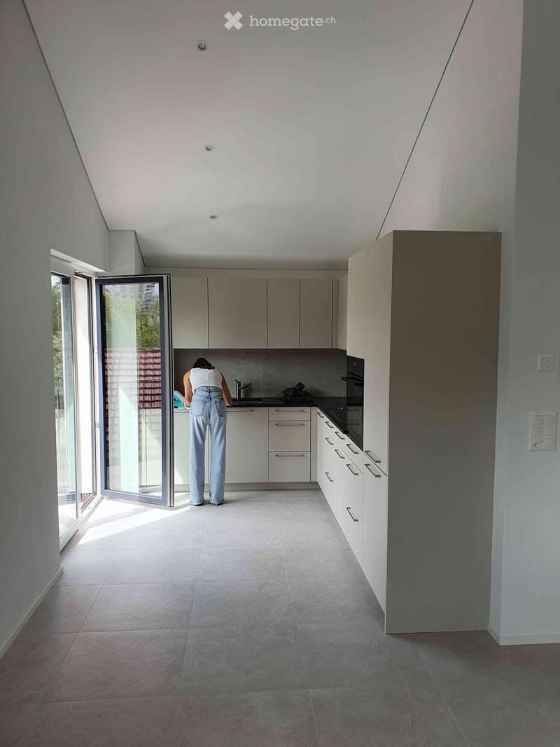 Modern kitchen with white cabinets, stainless steel appliances, and large glass doors leading to an outdoor area.
