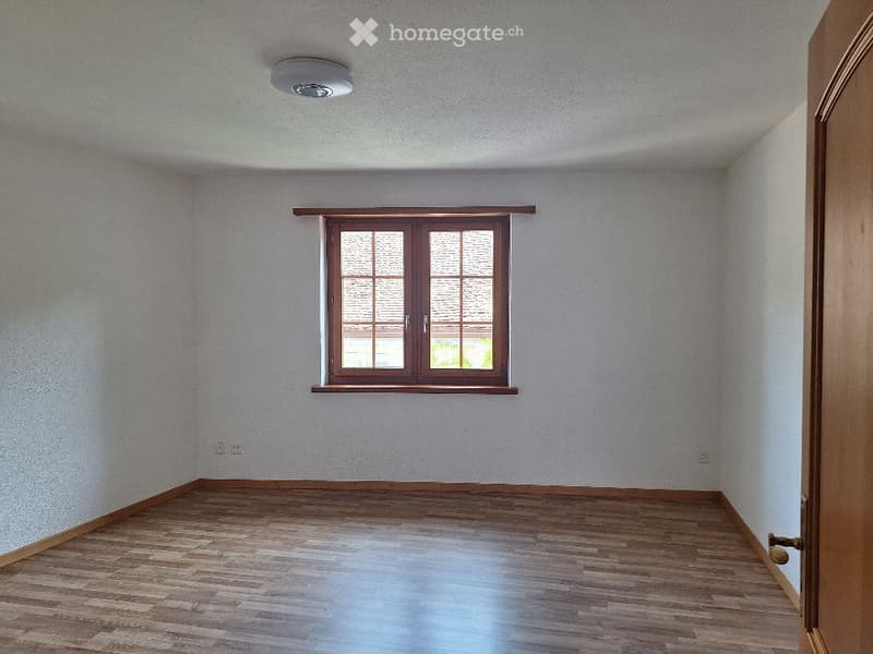 Empty room with wooden flooring, white walls, and a single window with brown frame. No furniture or equipment present.