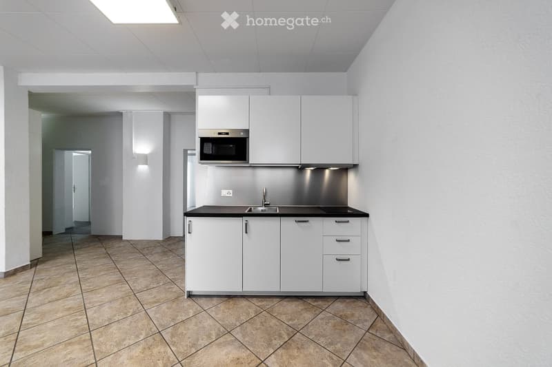 Modern kitchen with white cabinets, a microwave, a sink, and a faucet, featuring tiled flooring and white walls.
