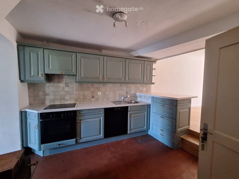 Modern kitchen with grey cabinets, white countertops, and a built-in oven. Features a sink with a modern faucet and a tiled backsplash.