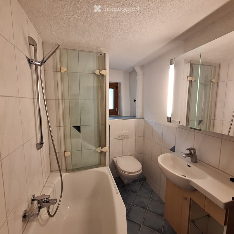 Modern bathroom with a bathtub, toilet, sink, mirror, and a glass-enclosed shower area.