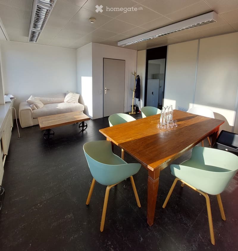 A modern, minimalist room with a sofa, coffee table, dining table, chairs, and a laptop on a side table.
