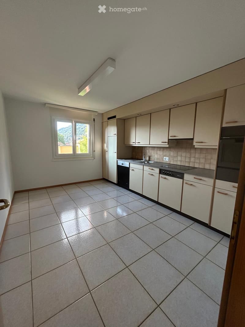 Empty kitchen with white cabinets, tiled floor, sink, oven, and dishwasher.