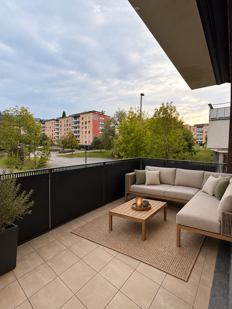 Balcony with a modern seating area featuring a beige sectional sofa, wooden coffee table, and cushions, surrounded by a black railing and greenery.