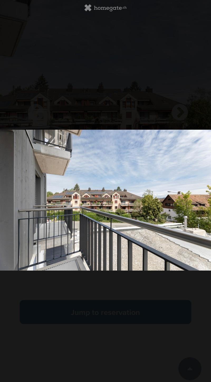 Balcony with metal railing overlooking a residential area with houses, trees, and solar panels on rooftops.