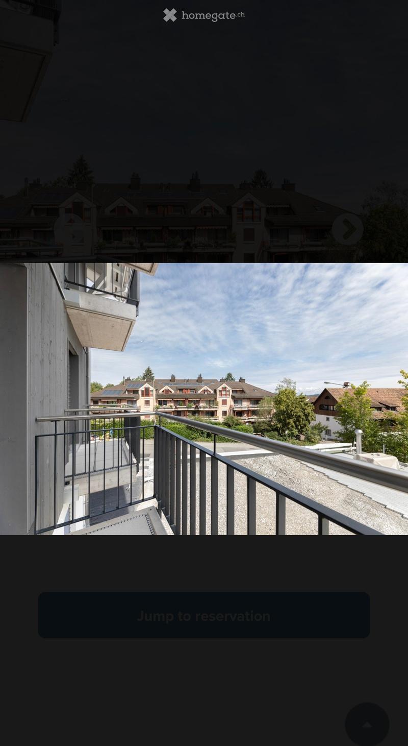 Balcony with metal railing, overlooking a residential area with multiple buildings and greenery.