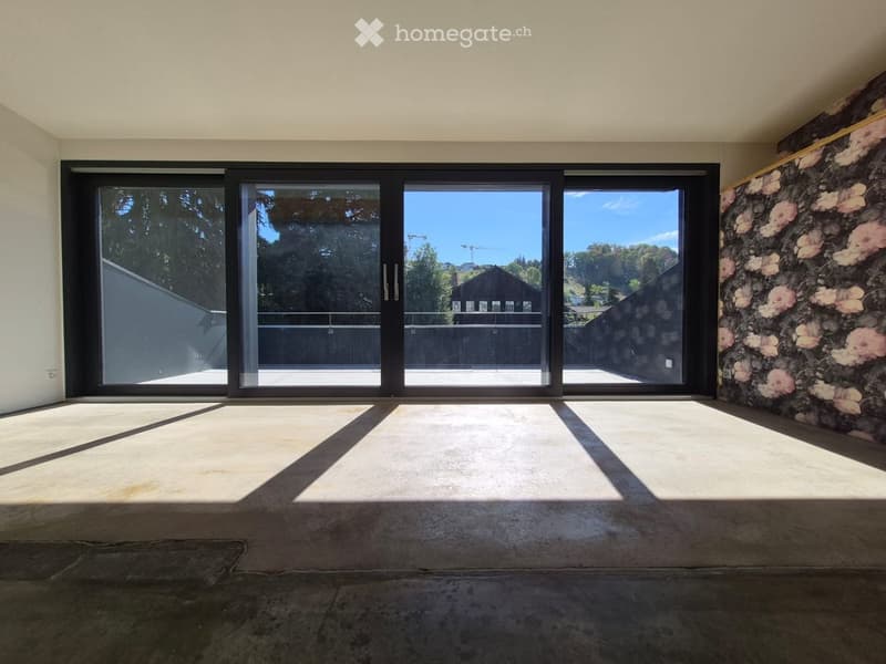 Empty room with large sliding glass doors, concrete floor, and floral wall mural.