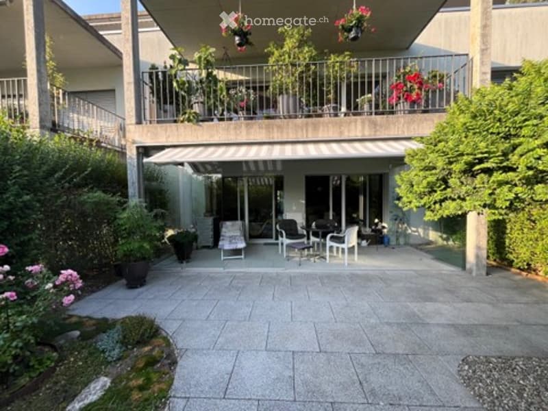 Balcony area with outdoor furniture, potted plants, and hanging flower baskets.