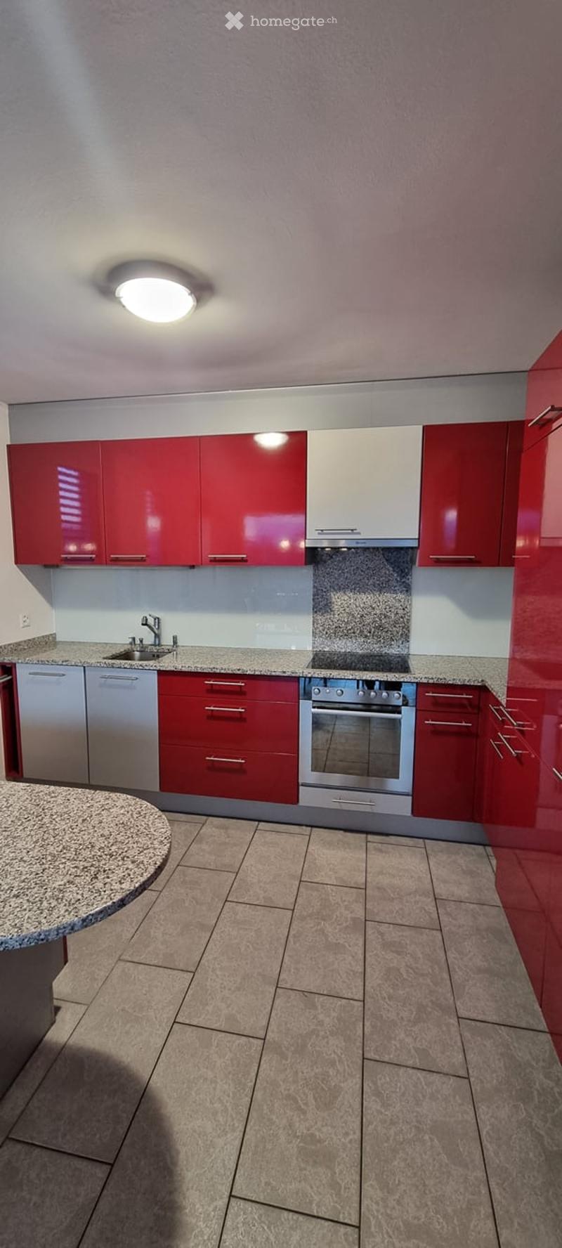 modern kitchen, red cabinets, granite countertop, silver appliances, white floor tiles, red cupboards, gas stove and oven, sink with faucet, overhead lighting, dishwasher and washing machine installed