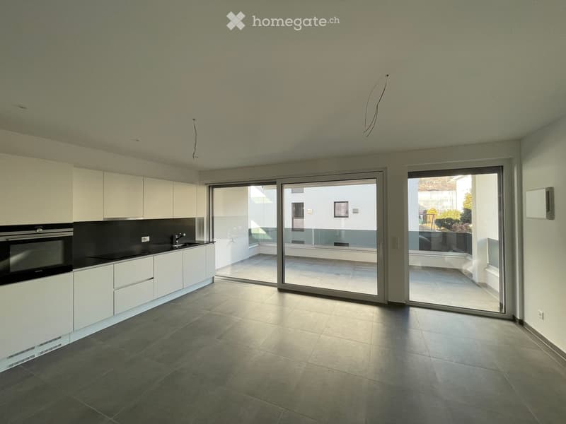 Modern kitchen with white cabinets, dark countertops, and large sliding glass doors leading to a balcony.